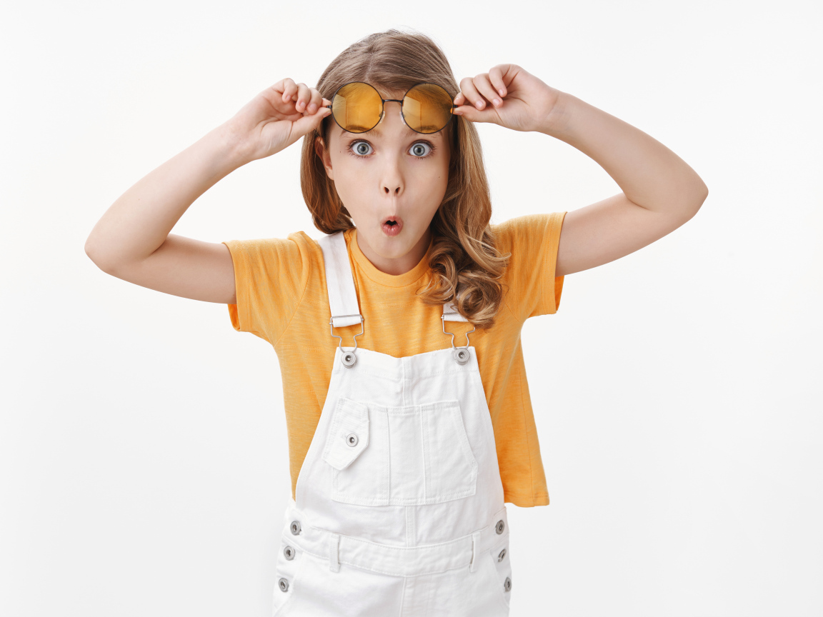 Удивленная девочка в очках на белом фоне