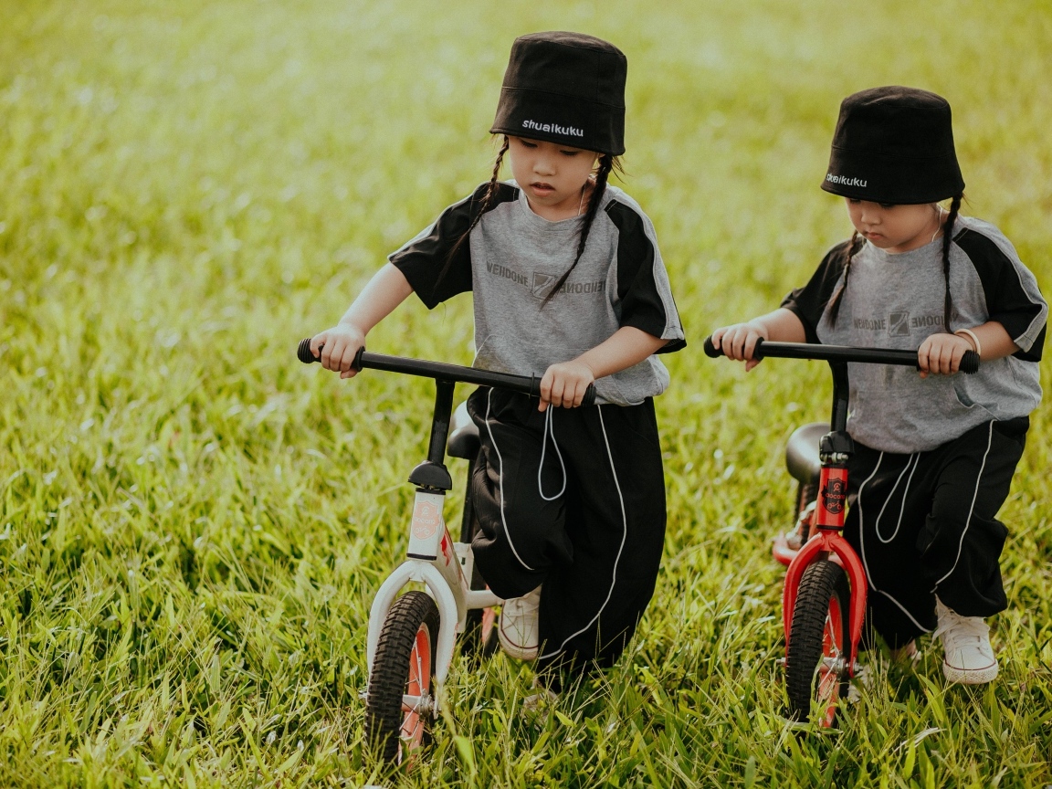 Две девочки с велосипедами на зеленой траве