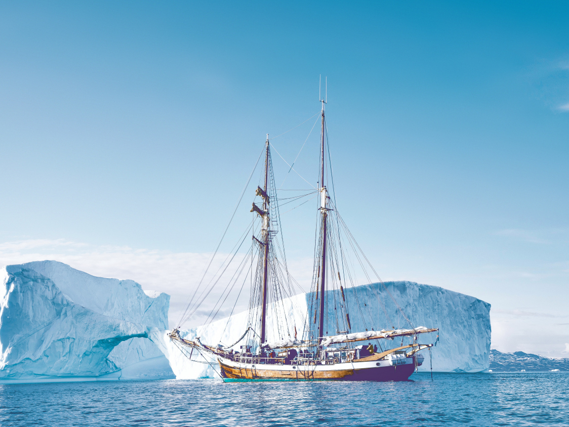 Большой корабль подплывает к голубому айсбергу в море