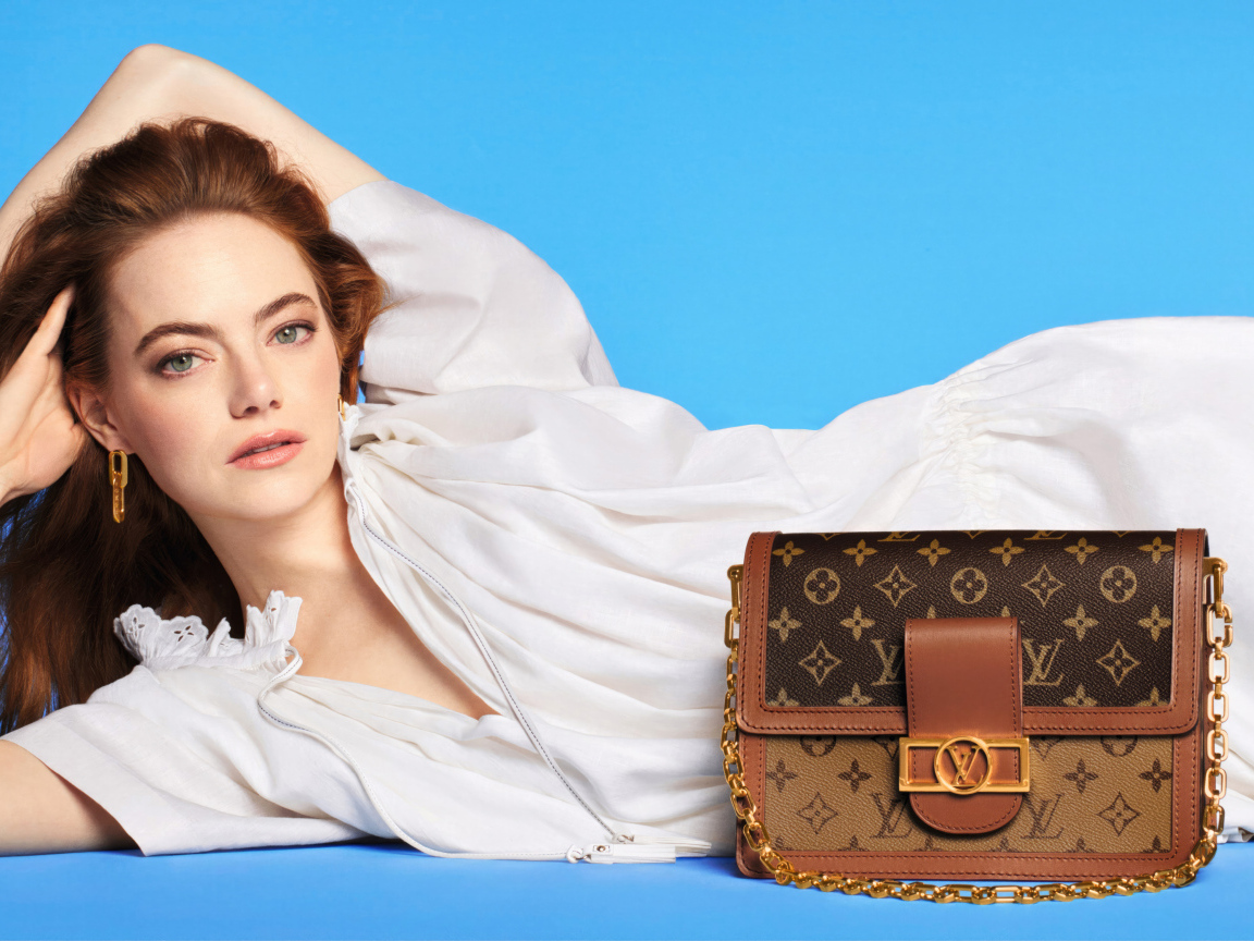 Актриса Эмма Стоун с сумочкой Louis Vuitton на голубом фоне
