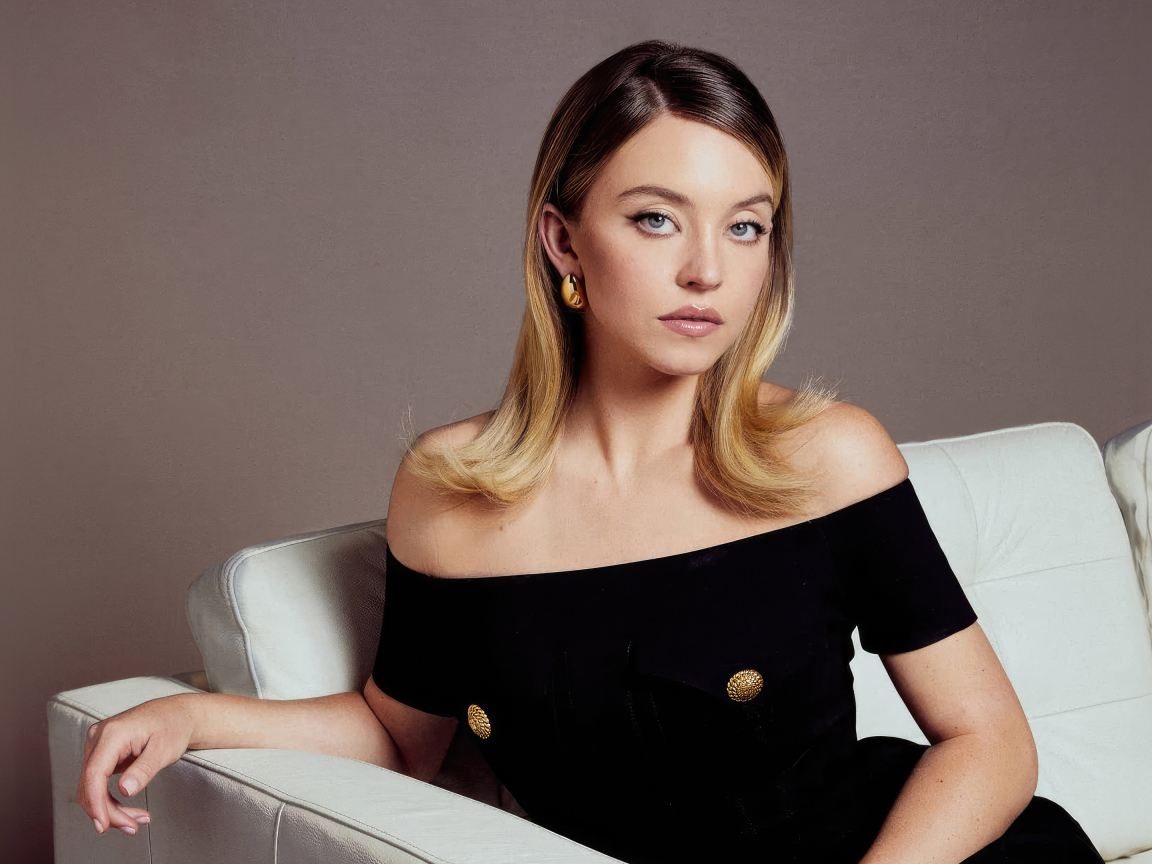 Актриса Сидни Суини в черном платье на белом диване