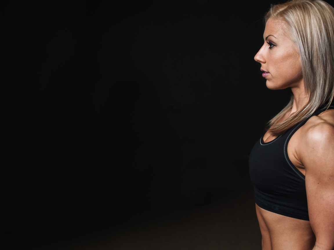 Спортивная блондинка стоит на черном фоне
