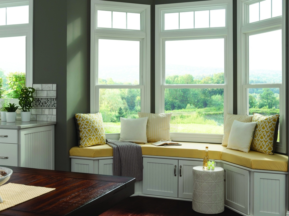 Уютная светлая кухня с эркером в загородном доме в зеленых тонах