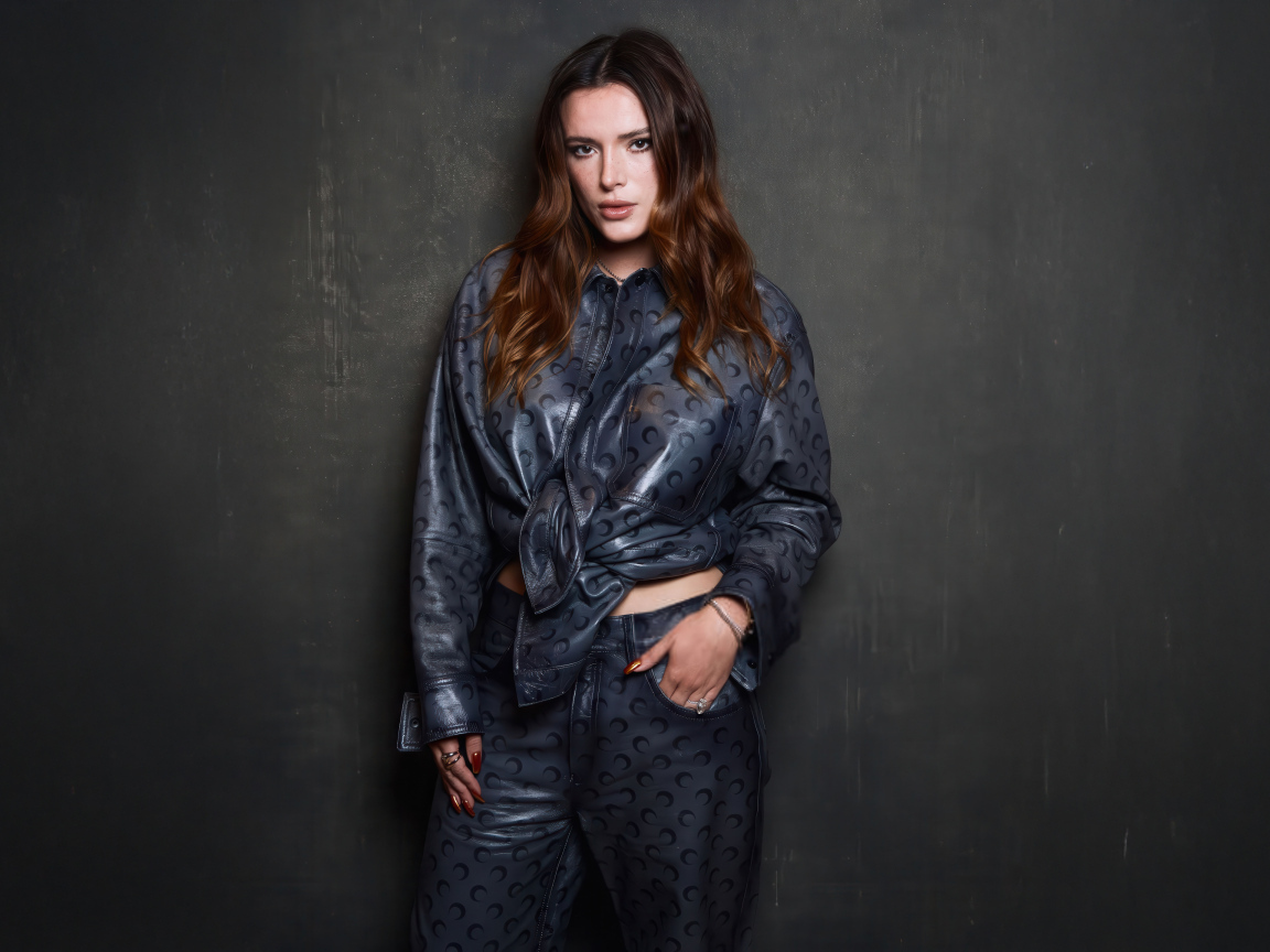 Рыжеволосая американская актриса Белла Торн в костюме на сером фоне