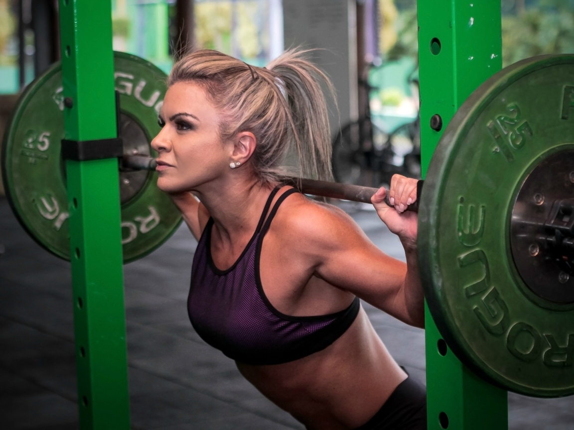 Сильная спортивная девушка поднимает штангу