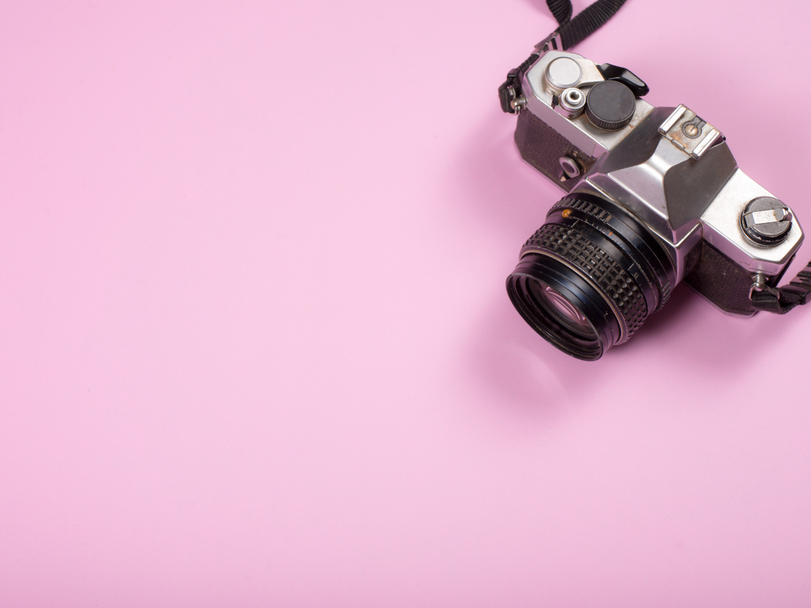 Старый фотоаппарат на розовом фоне
