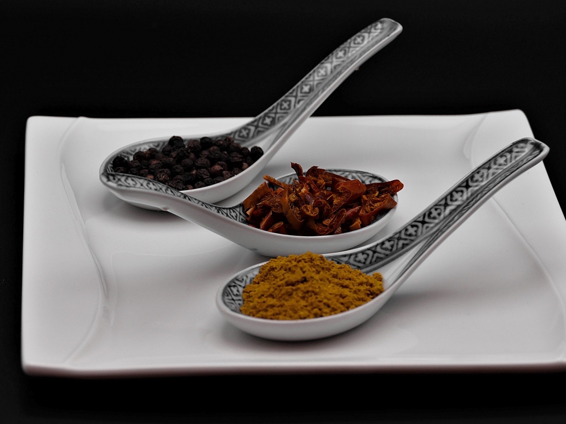 Ароматные специи в ложках на белой тарелке