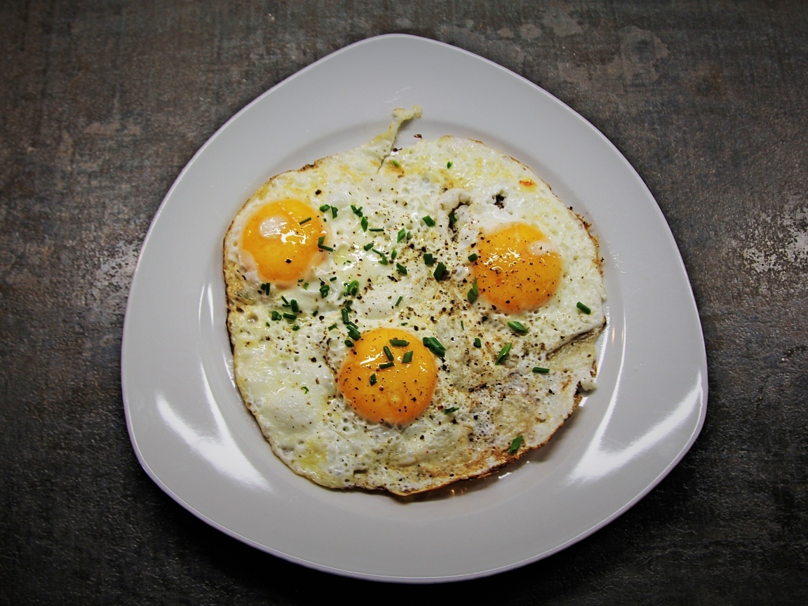 Яичница глазунья в тарелке на сером столе