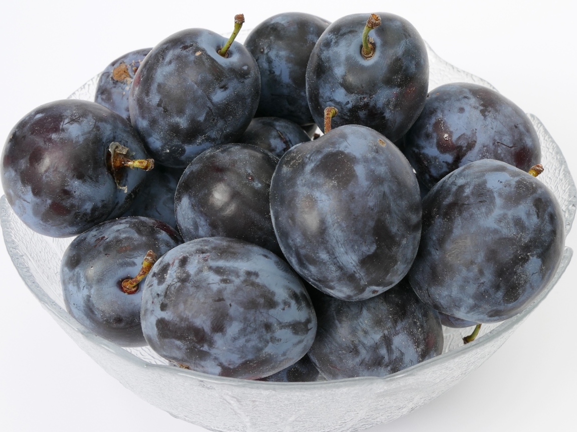 Стеклянная тарелка с вкусными синими сливами
