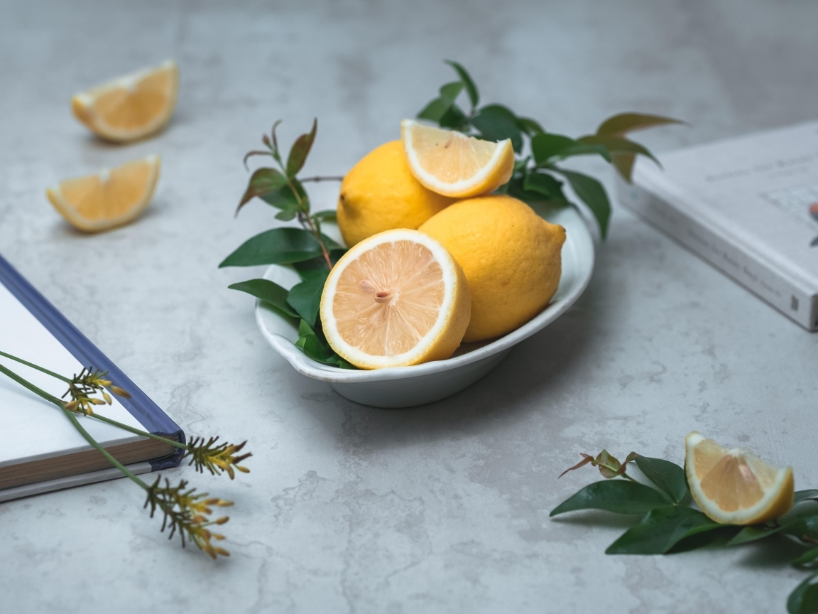 Лимон с зелеными листьями на столе с книгами