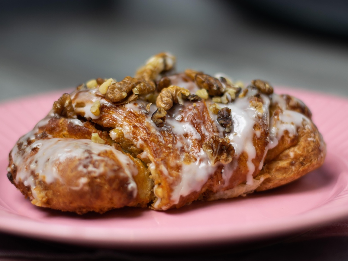 Круассан с кремом и грецкими орехами на розовой тарелке