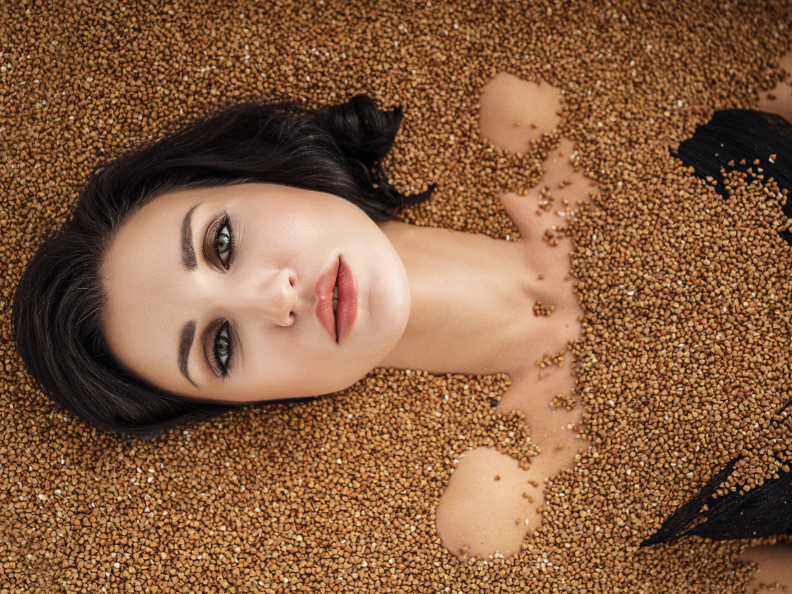 Красивая девушка лежит в зернах гречки