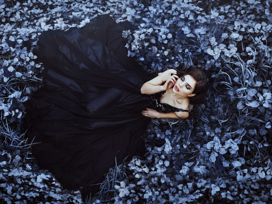 Девушка в черном платье лежит в траве