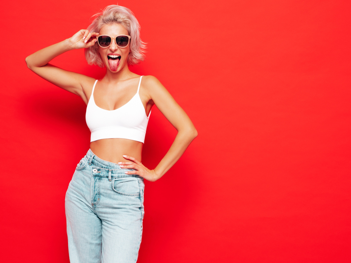 Девушка в очках с высунутым языком на красном фоне