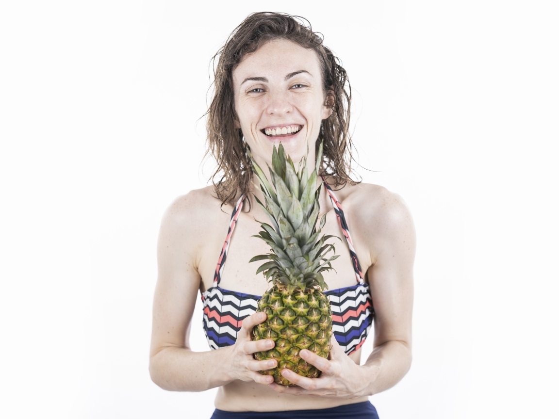 Улыбающаяся девушка с ананасом в руках