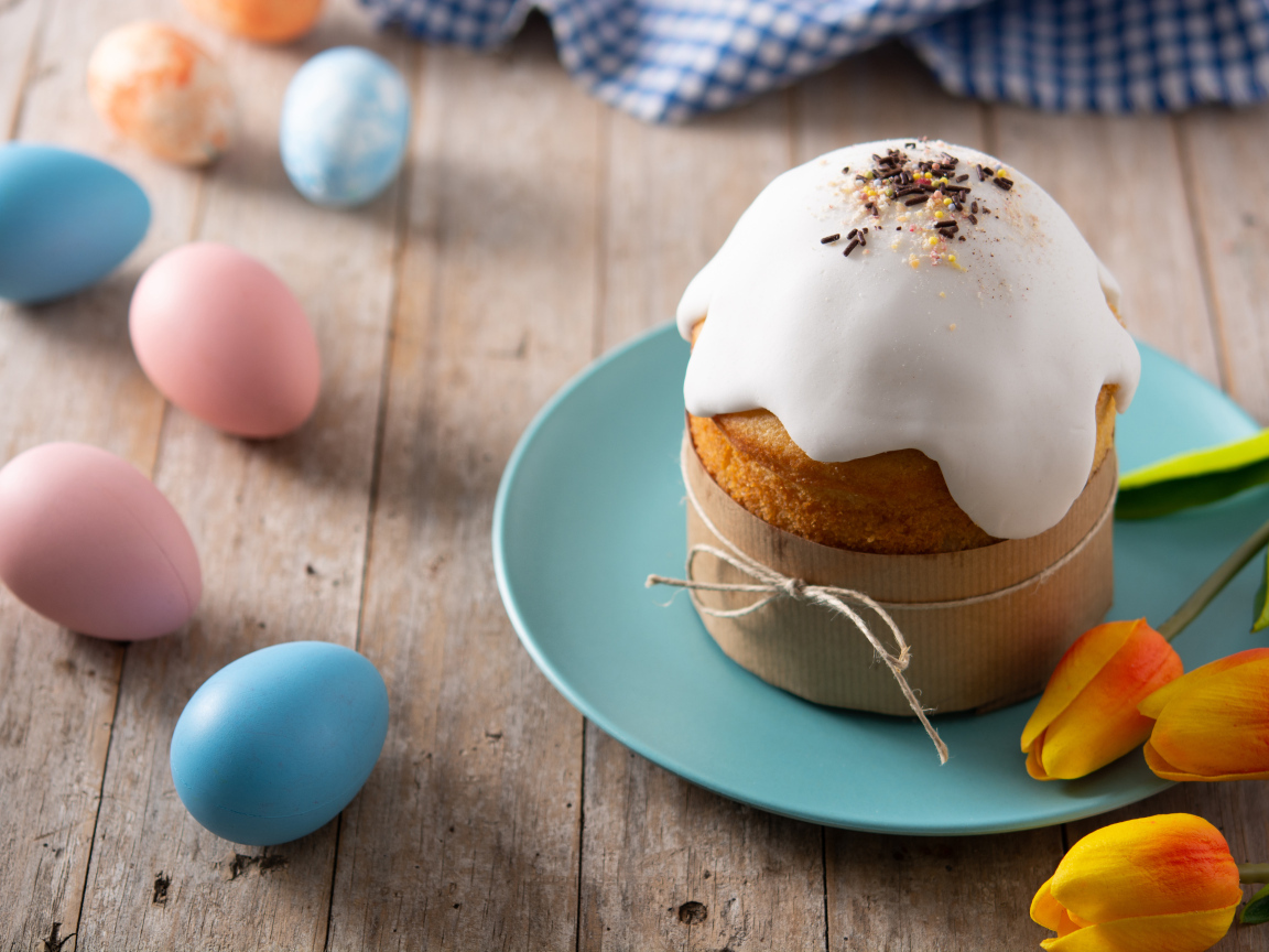 Кулич с крашеными яйцами и цветами на столе на Пасху