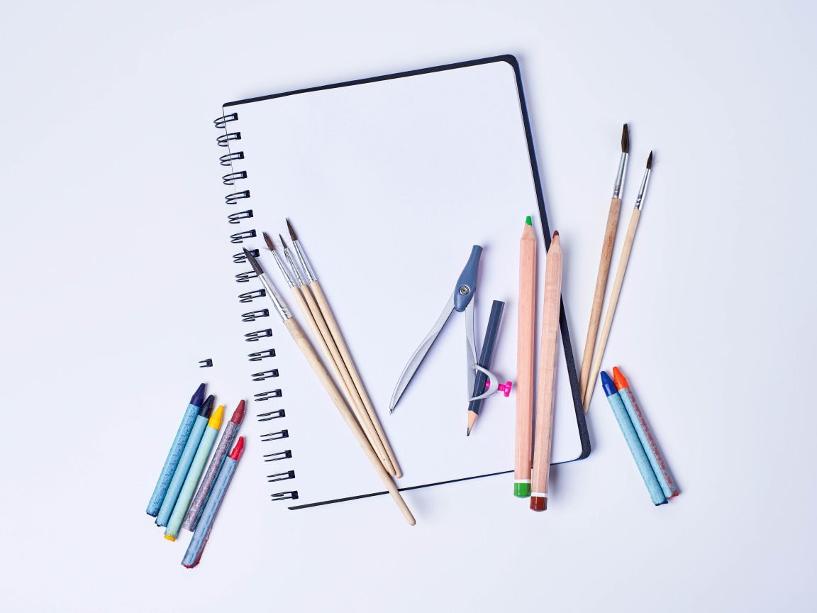 Карандаши, кисти и блокнот для рисования на сером фоне