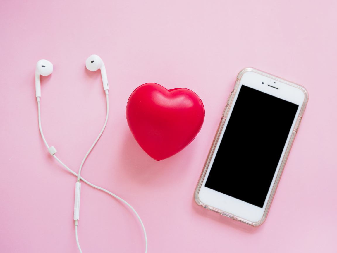 Телефон, наушники и красное сердце на розовом фоне