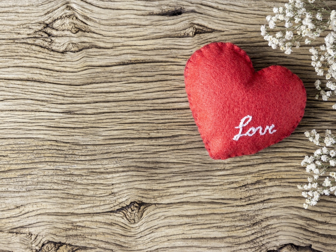 Красное тканевое сердце с цветами на деревянном столе