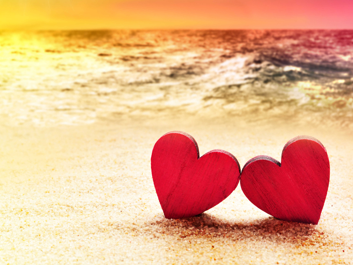 Два красных сердечка на песке на пляже