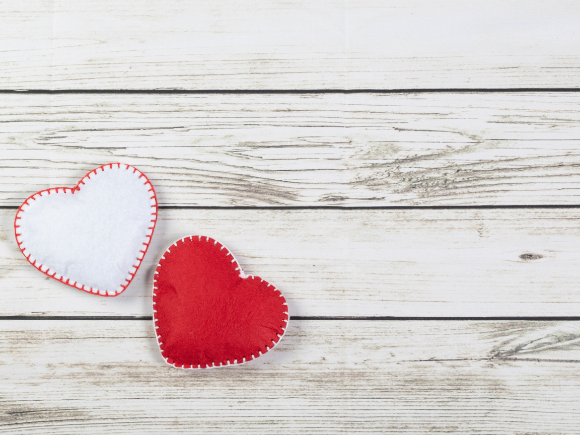 Белое и красное сшитое сердце на деревянном фоне