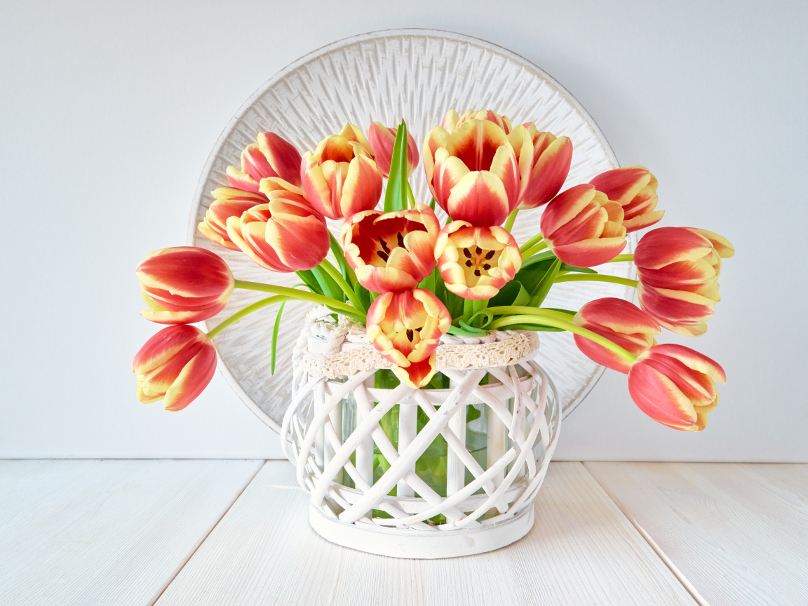 Красивый букет оранжевых тюльпанов в белой вазе на столе