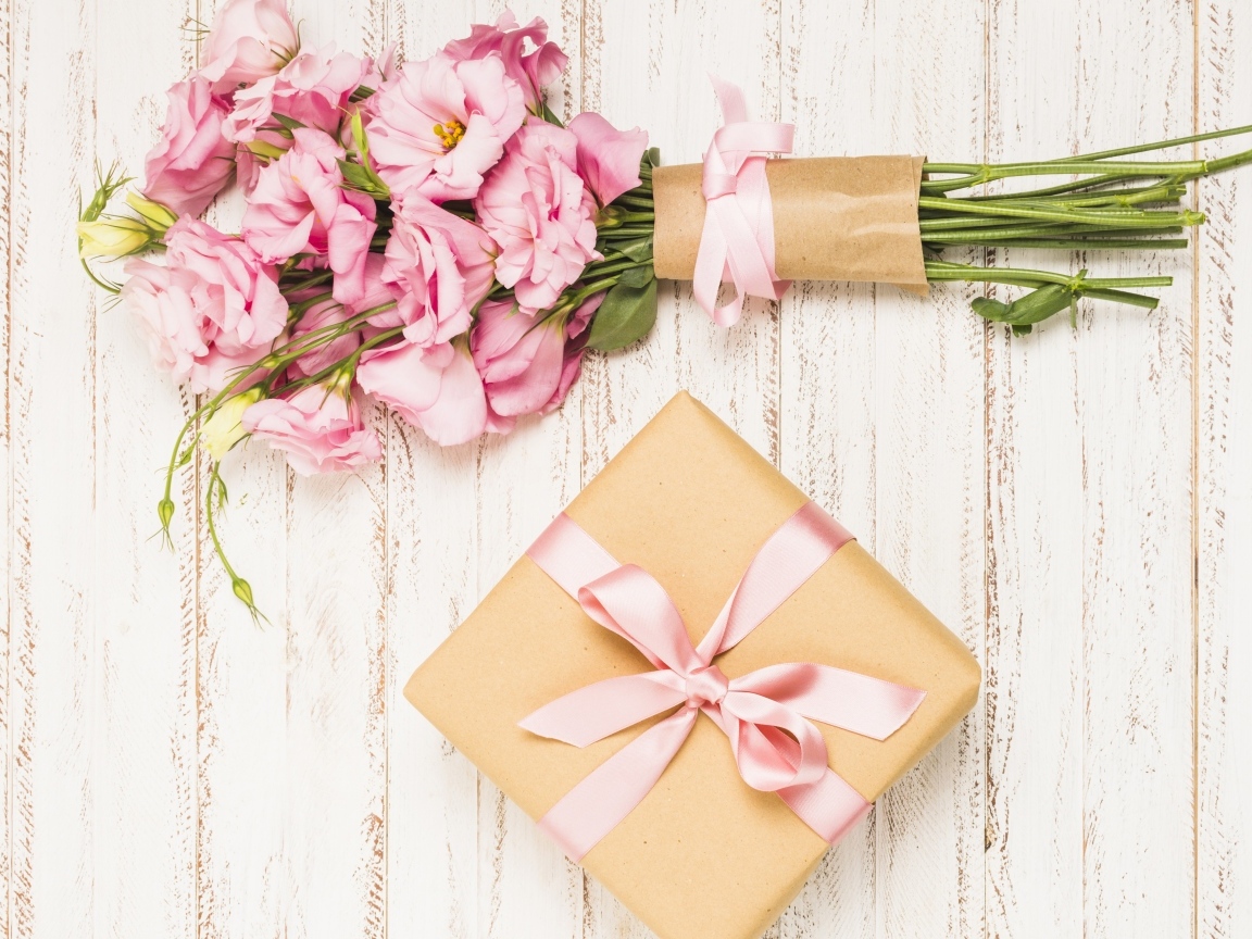 Букет розовых цветов эустомы с подарком на деревянном фоне