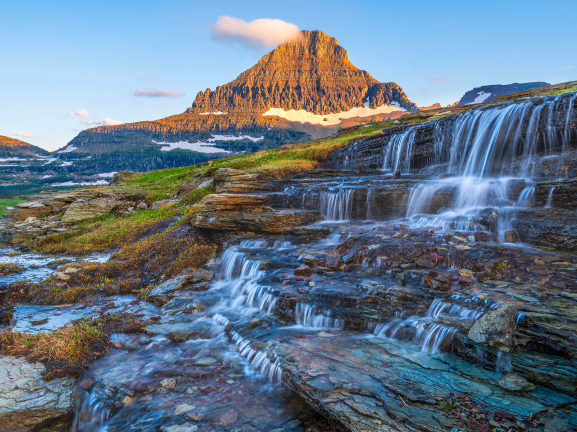 Водопад стекает по камням у высокой горы
