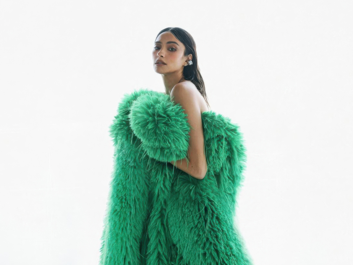 Актриса Шэй Митчелл в зеленой шубе на белом фоне