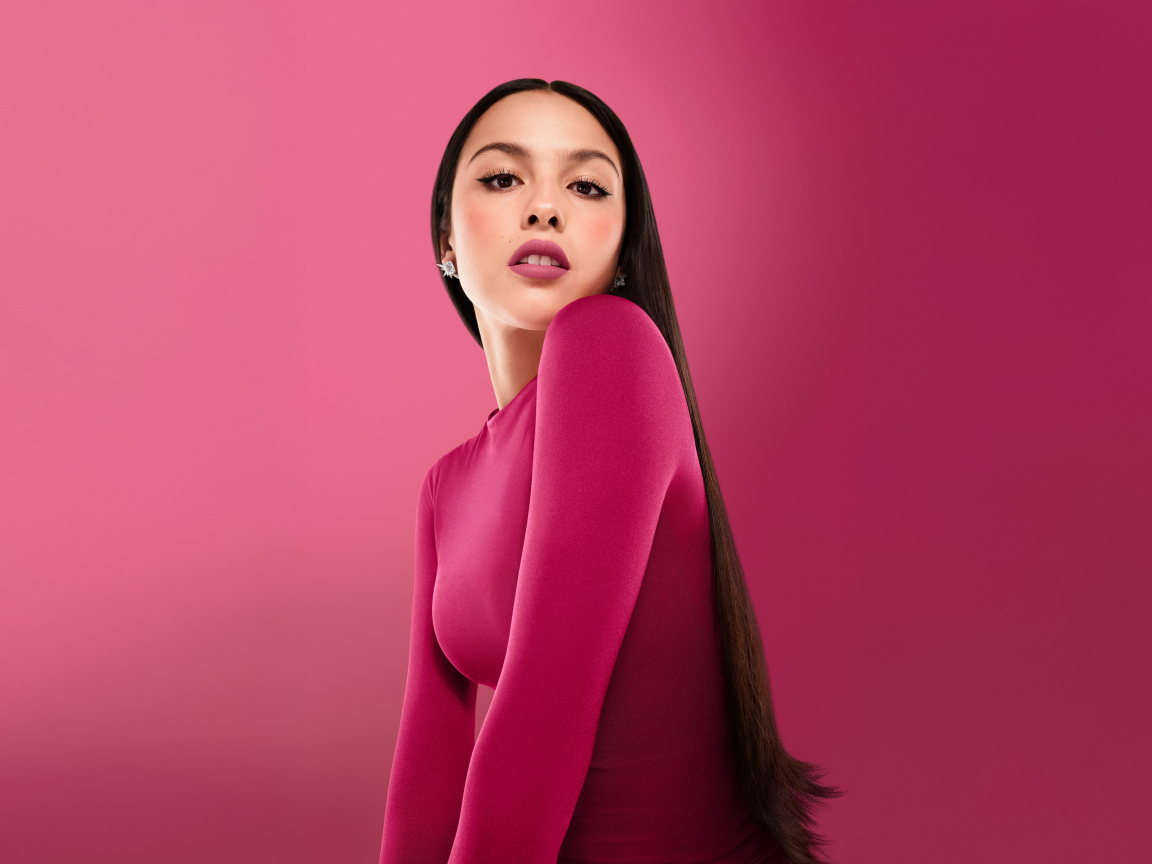 Длинноволосая актриса Оливия Родриго на розовом фоне