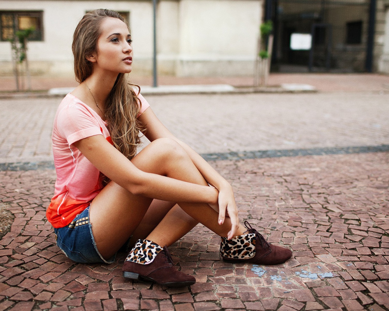 Брюнетка в шортах сидит на дороге