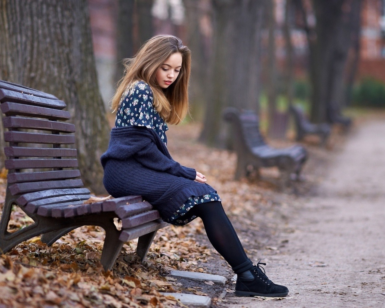 Симпатичная девушка сидит в осеннем парке