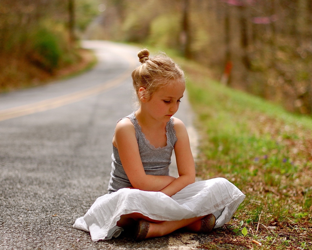 Девочка сидит на обочине дороги