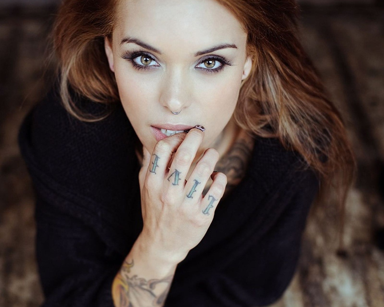 Девушка шатенка с пирсингом в носу и татуировкой на руке