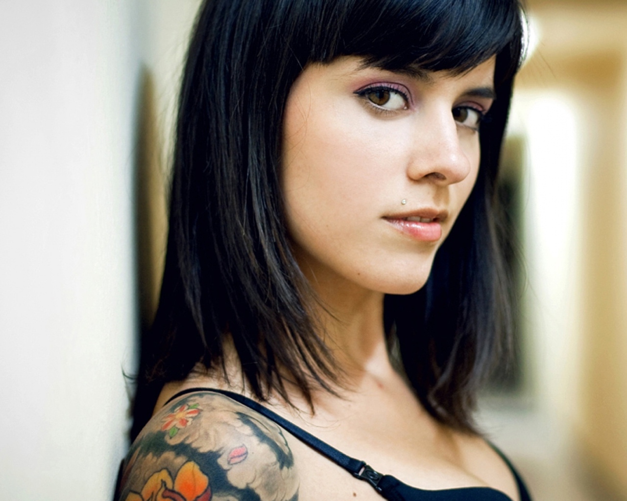 Девушка брюнетка с пирсингом в губе и татуировкой на плече