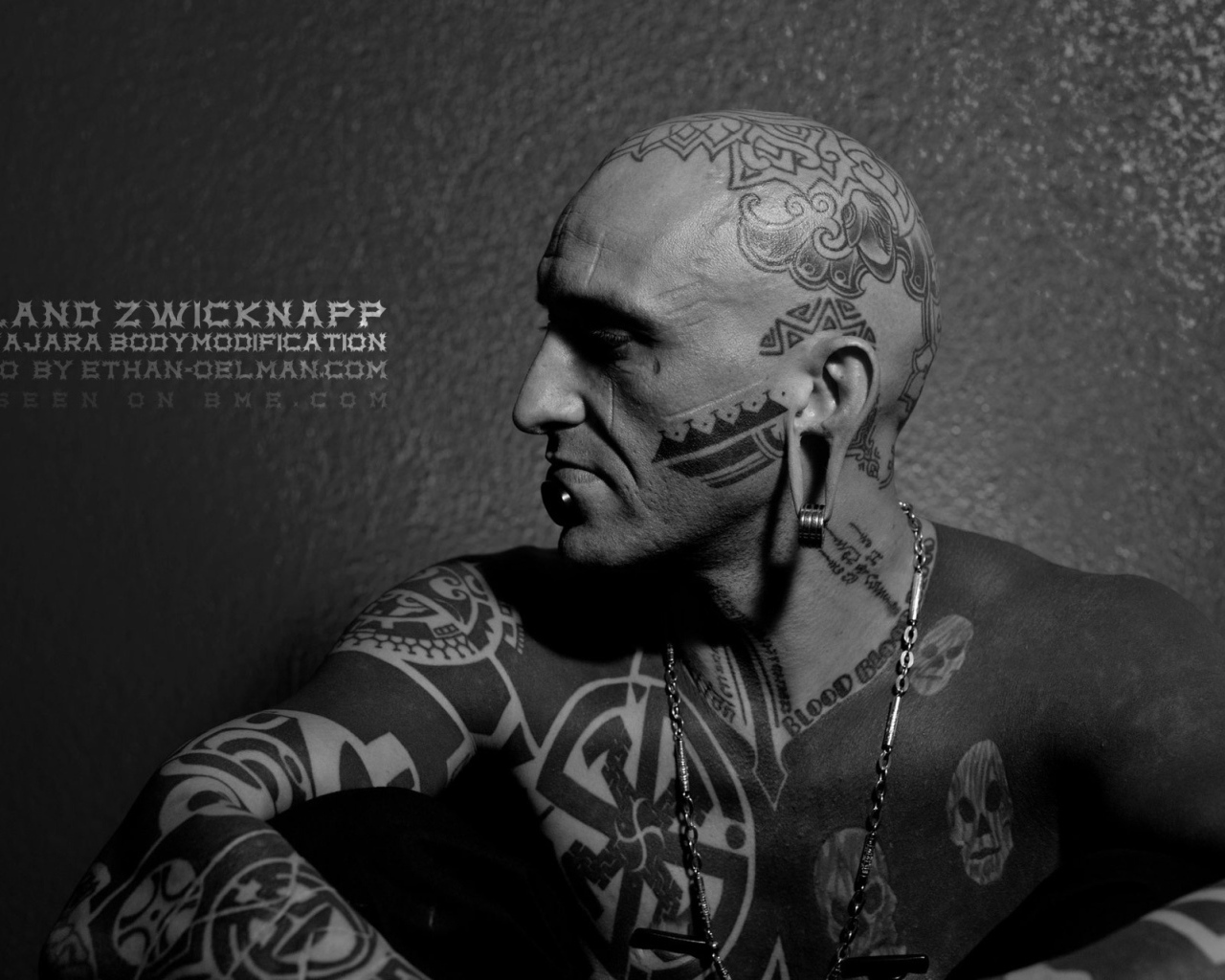 Мужчина с пирсингом в губе и татуировками