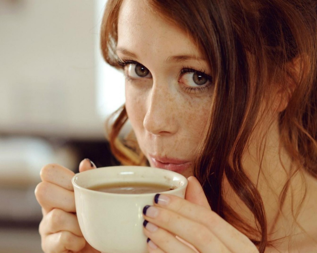 Девушка с веснушками пьет кофе
