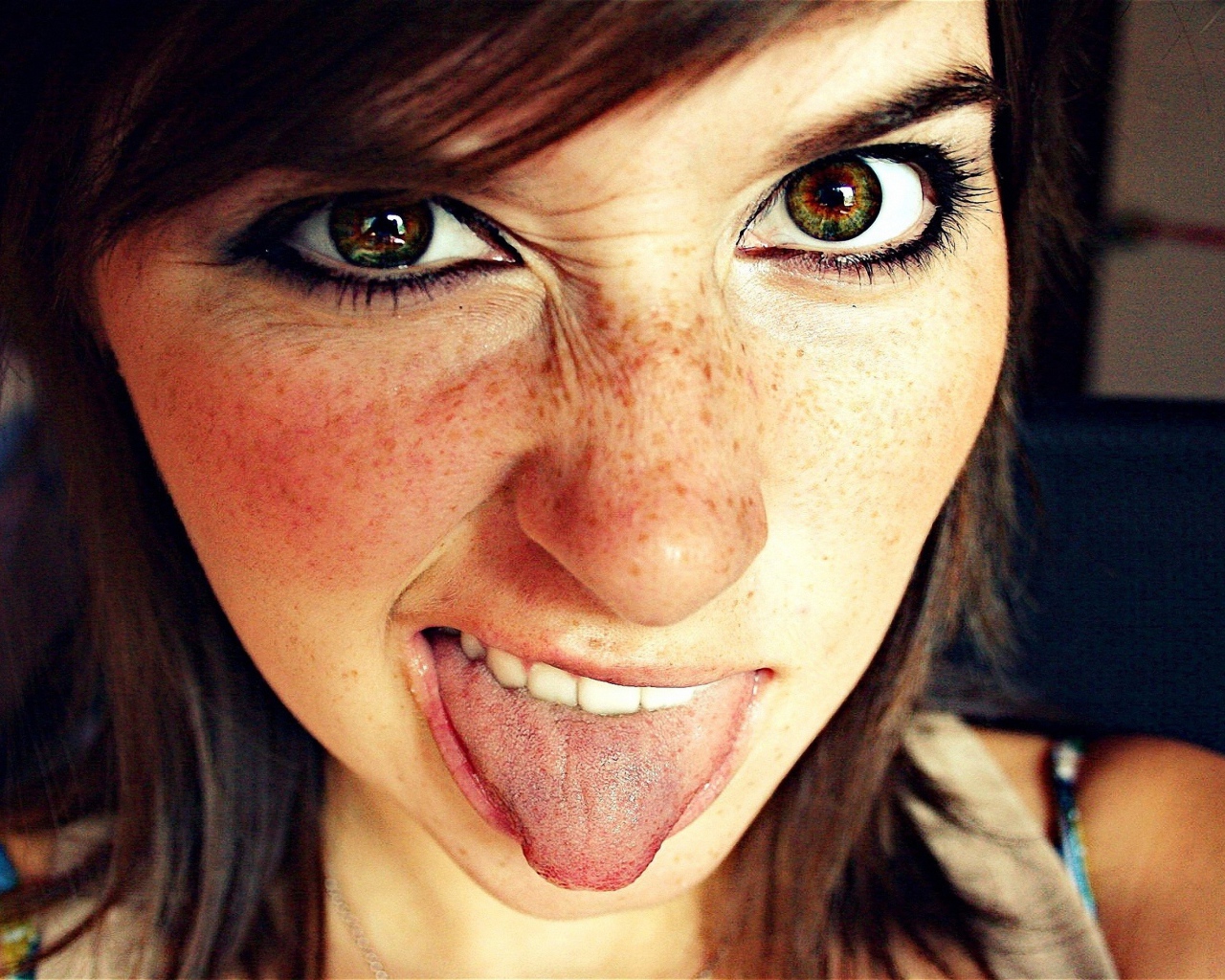 Девушка с веснушками показывает язык