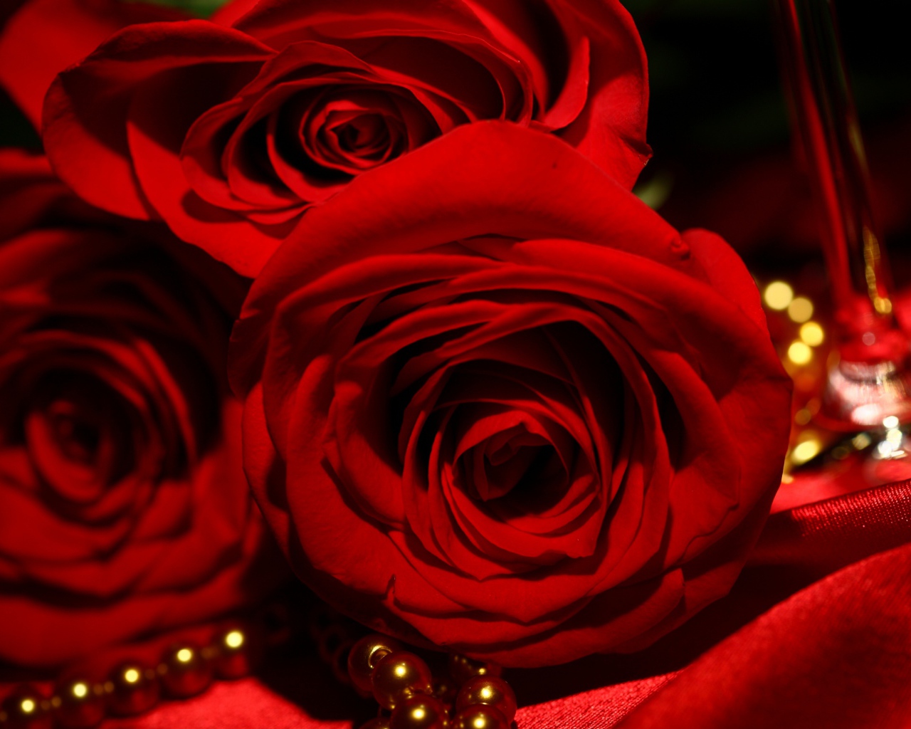 Красные розы на 8 марта на фоне атласа и жемчуга