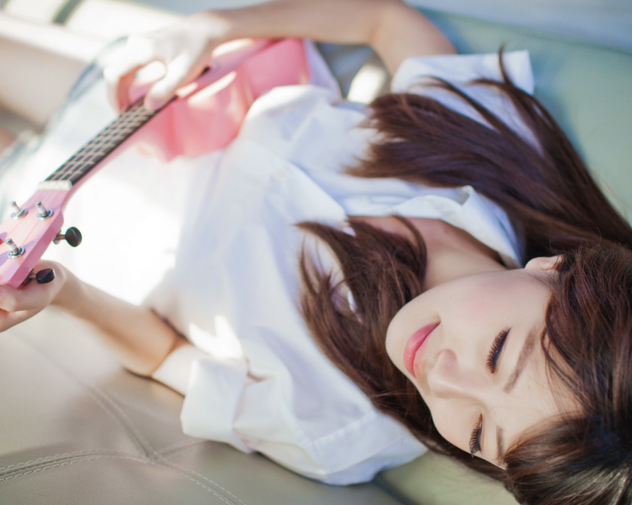 Брюнетка и розовая гитара на диване