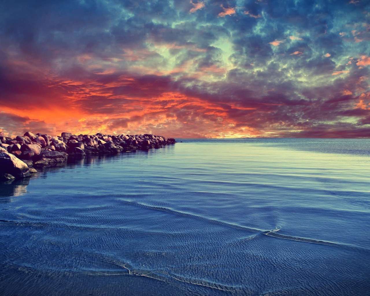 Красный закат над каменистым берегом