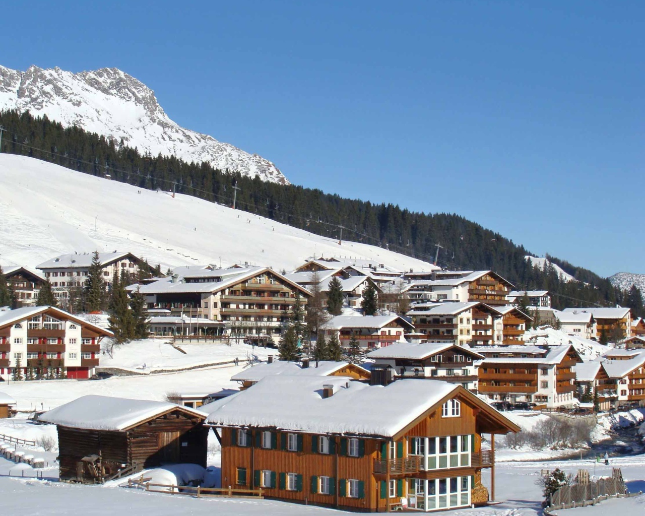 Дома на фоне гор на горнолыжном курорте Лех, Австрия