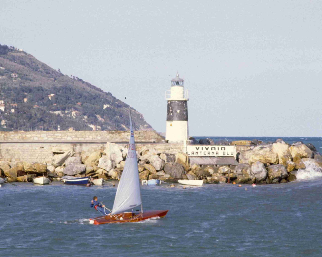 Лодка на фоне маяка на курорте Империя, Италия