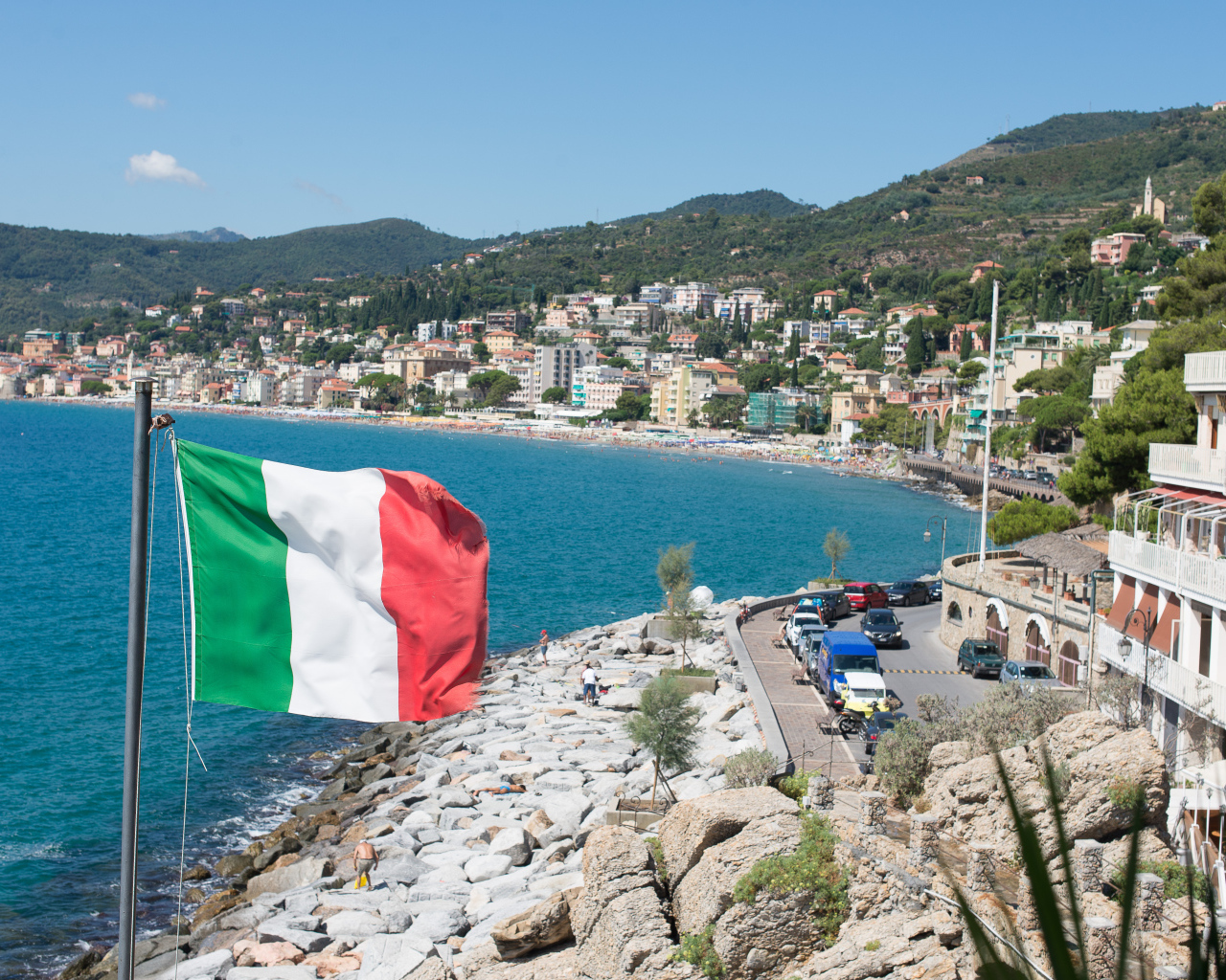 Флаг на фоне пляжа на курорте Алассио, Италия