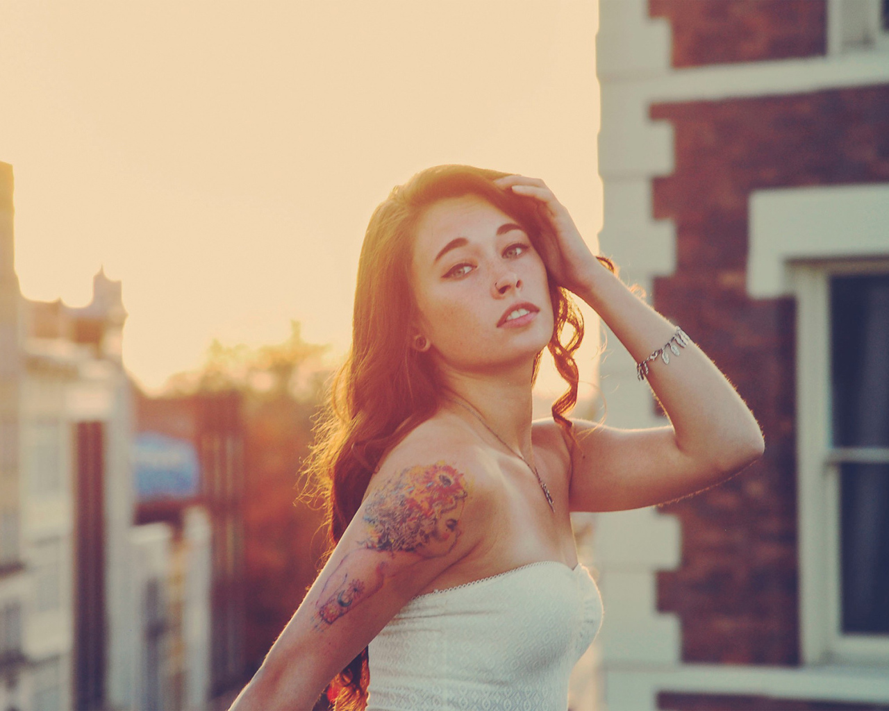 Девушка на закате с татуировкой на плече