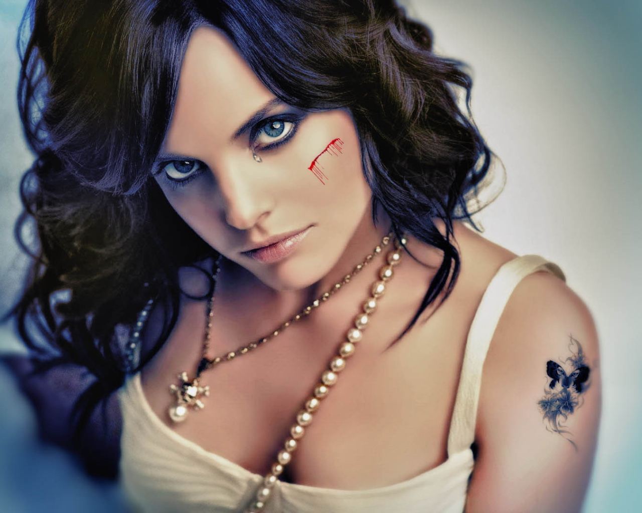 Шрам на щеке и татуировка на плече у девушки