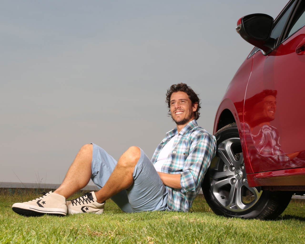 Мужчина сидит у колеса своего автомобиля