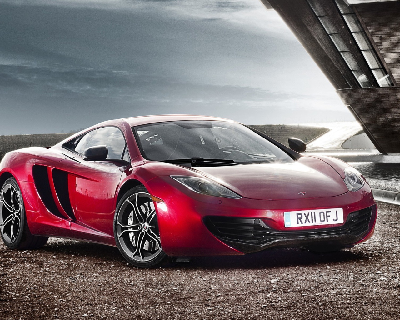 Красный McLaren на коричневом гравии