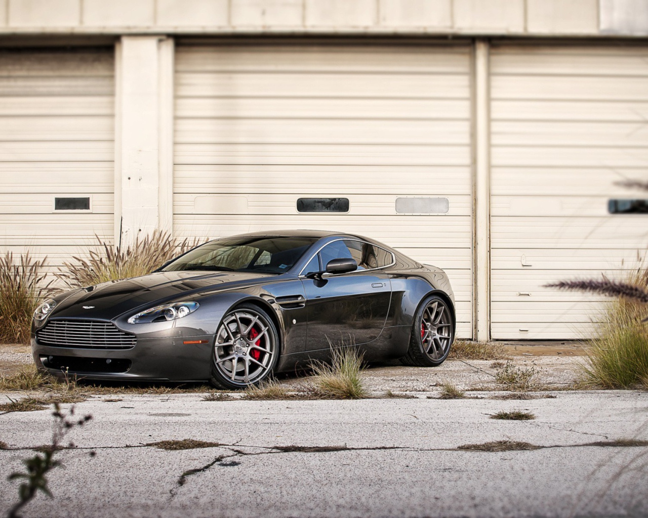 Черный Aston Martin в ворот белого ангара