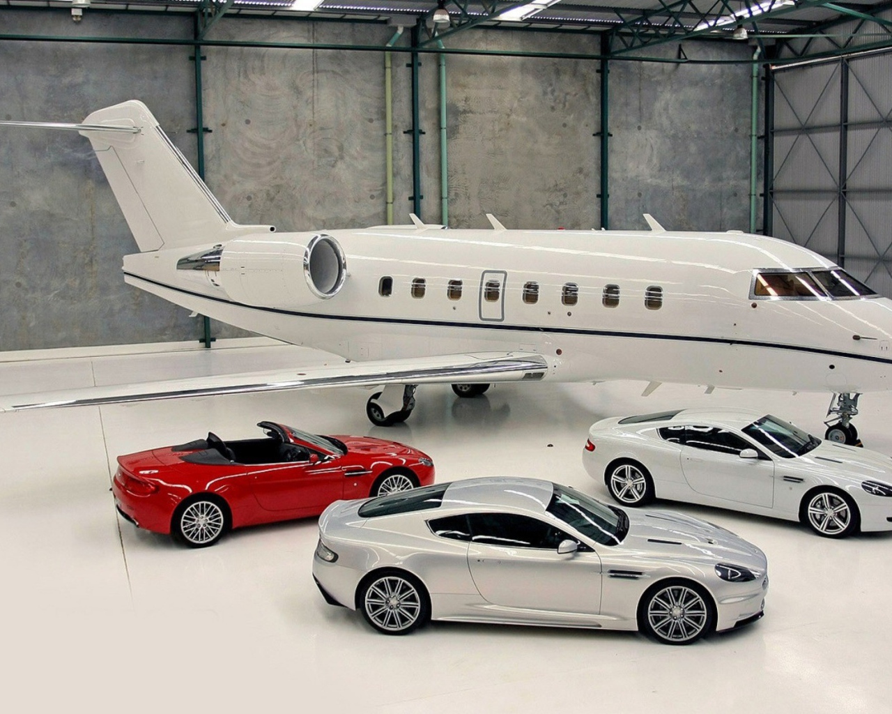 Автомобили Aston Martin в ангаре у частного самолета